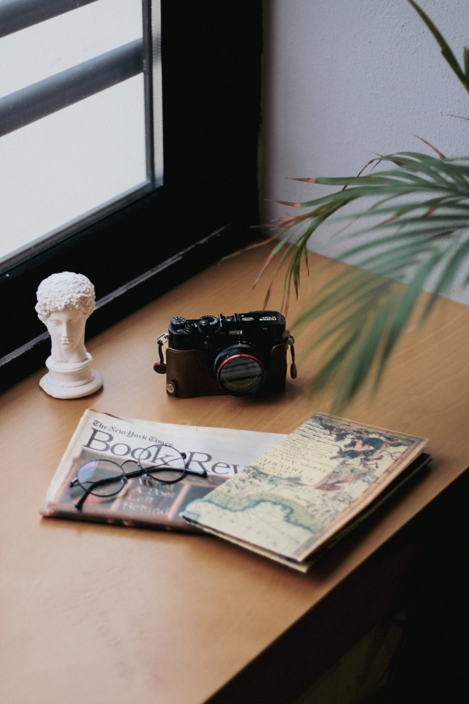 Newspaper and Camera on desk.